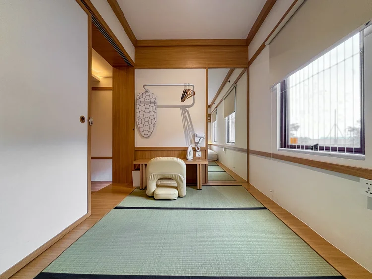 Omotesando: Tatami flooring in the bedroom, with a small stool and wall hangers.