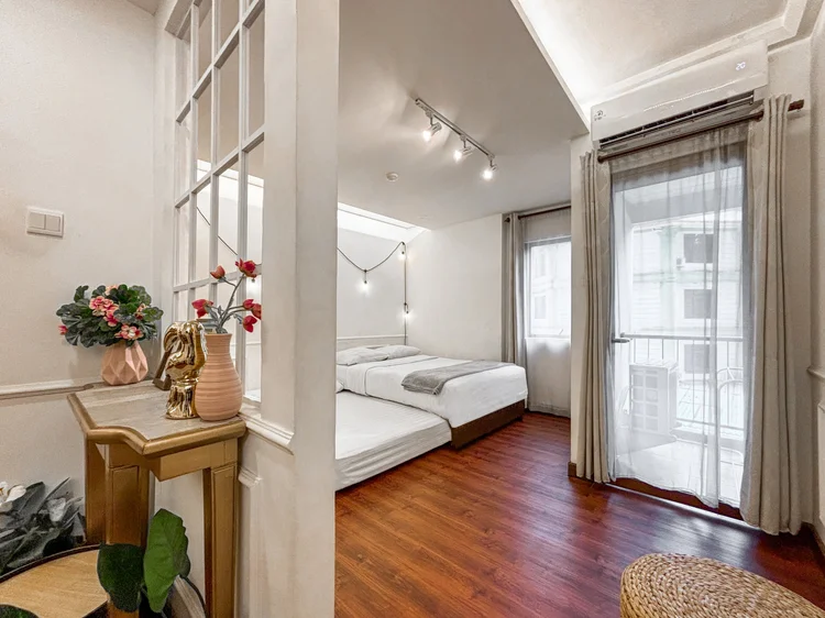 Provence: The bed area seen from the living room, with curtains and a door to the small balcony.