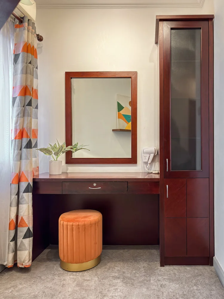 Chicago: Dressing table with a mirror and orange stool, for getting ready before heading out.