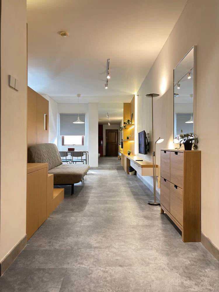 Helsinki: A hallway with a mirror and wood cabinets, linking the bed area and living room.