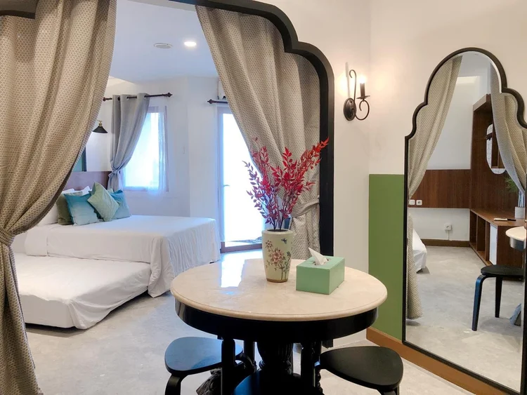 Saigon: A Peranakan-themed studio: bed, round dining table and a door to the small balcony.