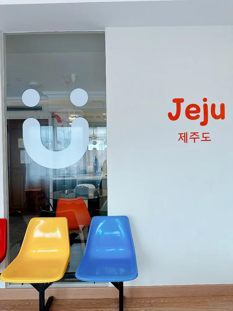 Jeju: A corner with the Jeju wall graphic and colorful chairs for extra seating.