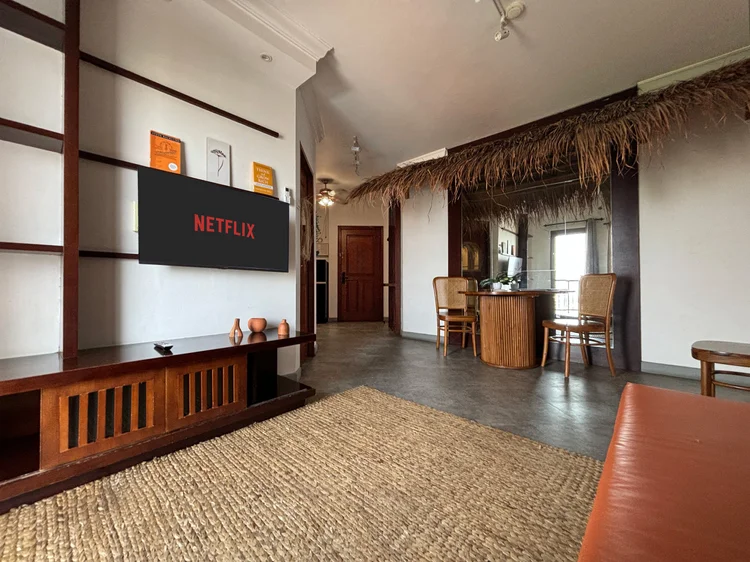 Ubud: Smart TV with Netflix on the wood unit, a woven rug covering the living room floor.