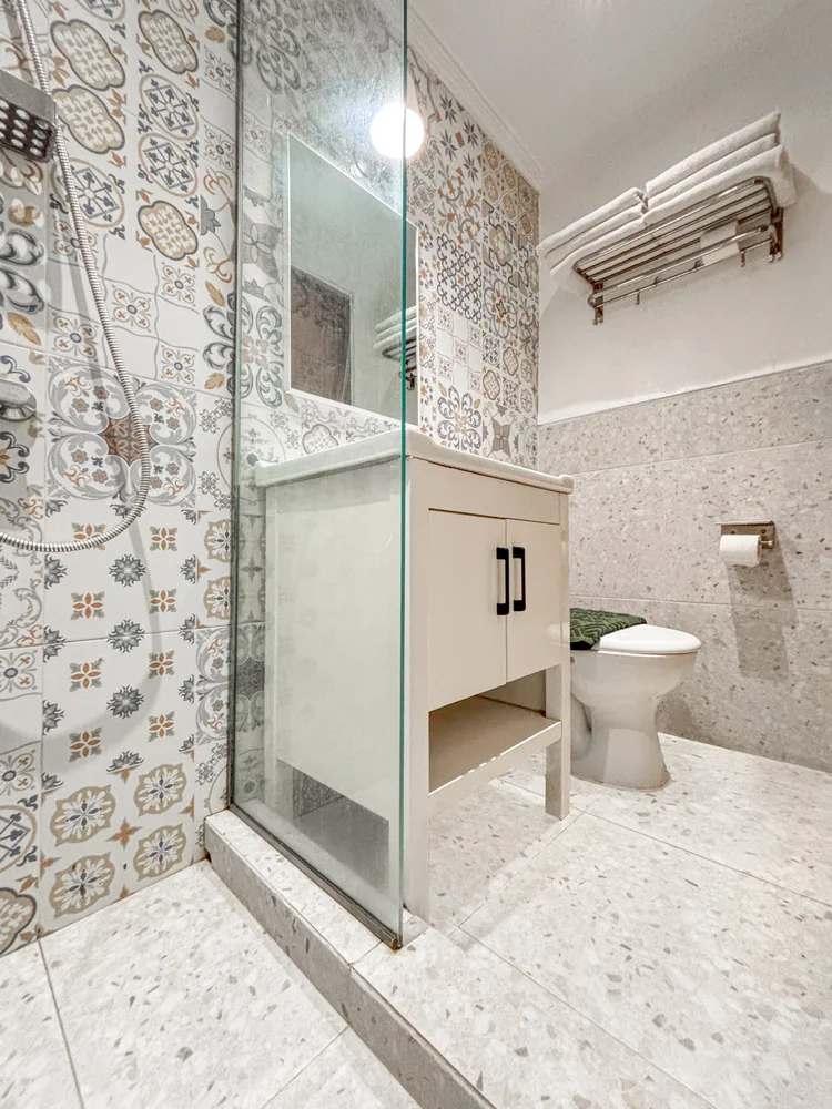 St. Tropez: Modern bathroom with patterned tiles, a glass-walled shower and a vanity basin.