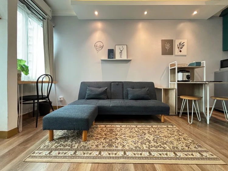 Bern: Air-conditioned sitting area with a rug, roomy for a 28 sqm studio.