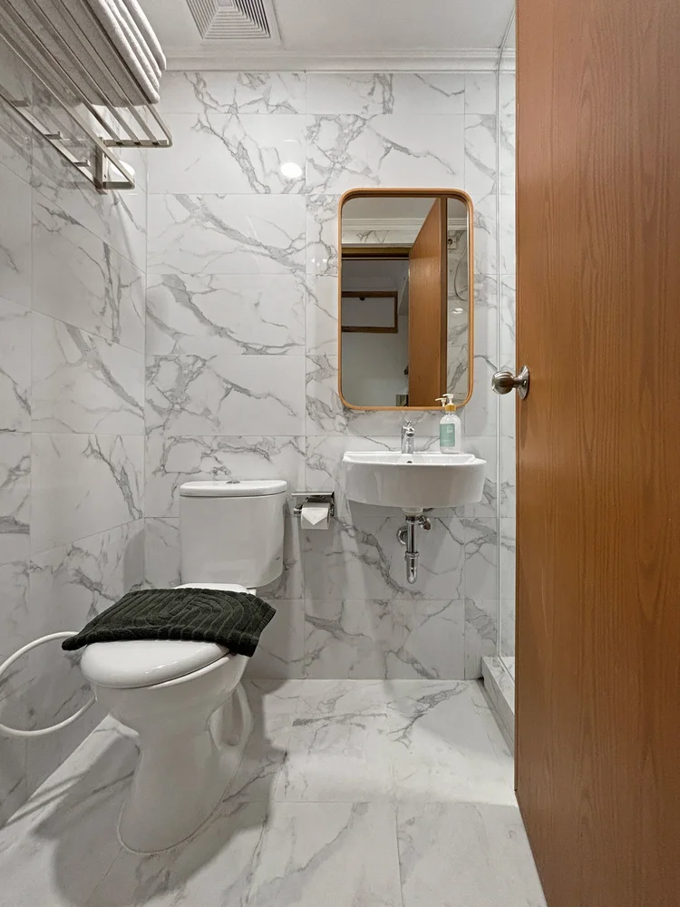 Hokkaido: Modern bathroom in marble-look tile, with basin and mirror.