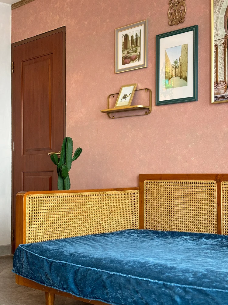 Marrakech: The day bed's rattan back, a cactus and frames on the pink wall.