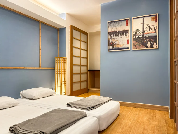 Yokohama: A bedroom with a blue wall and two beds, white sheets the same standard in all our units.