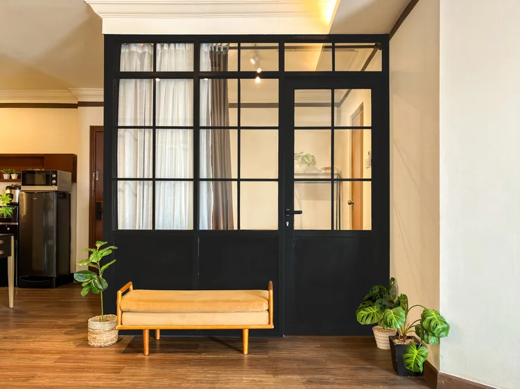 Norfolk: A black-framed glass partition with a wooden bench, the fridge alongside.