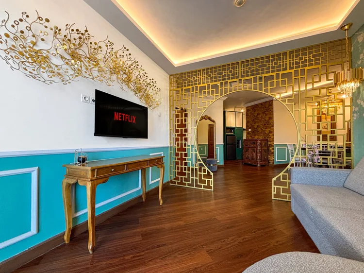 Salzburg: Chinoiserie living room: gold lattice screen, smart TV with Netflix and a console table.