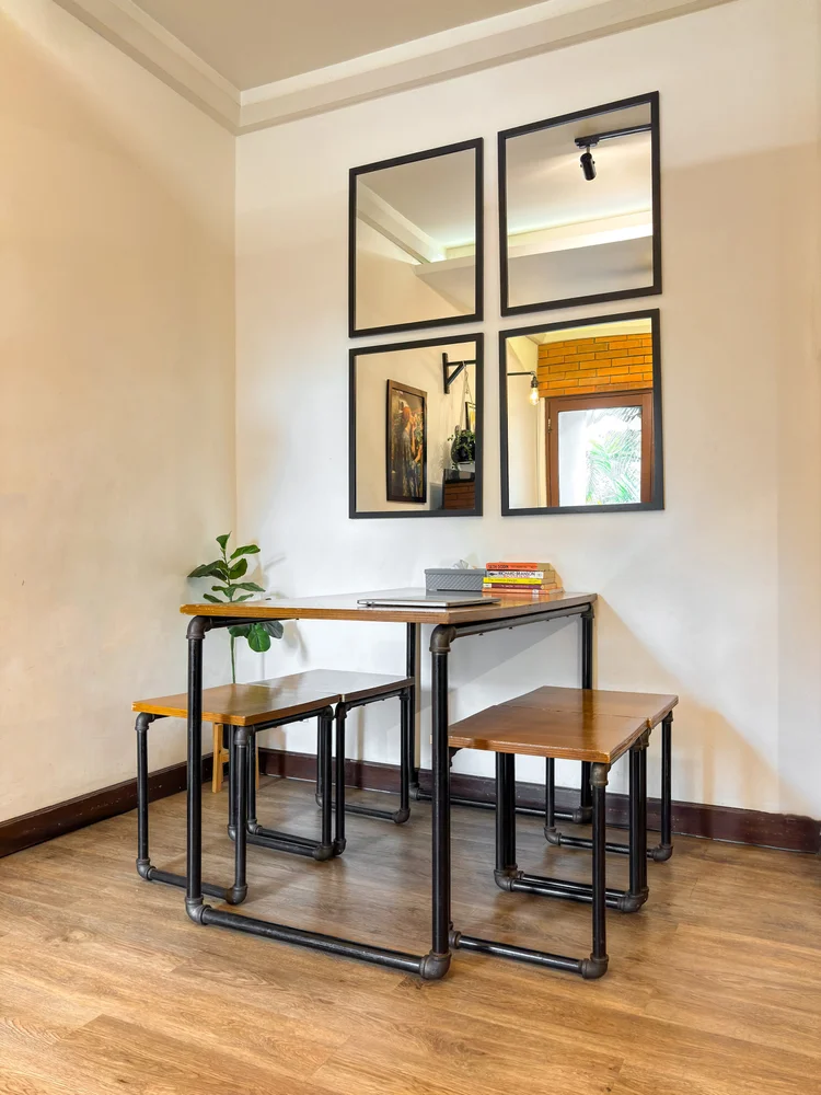Brooklyn: Dining table for 4 with stools, and black-framed mirrors on the wall.