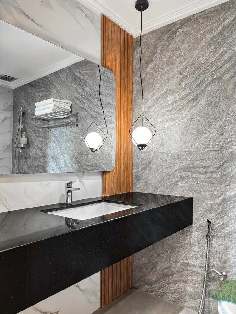 Salzburg: Basin on a black counter with grey marble walls, a pendant lamp above.