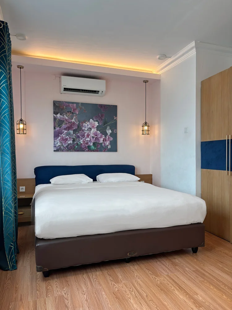 Beverly: A bedroom with its own AC and wardrobe, a floral painting above the headboard.
