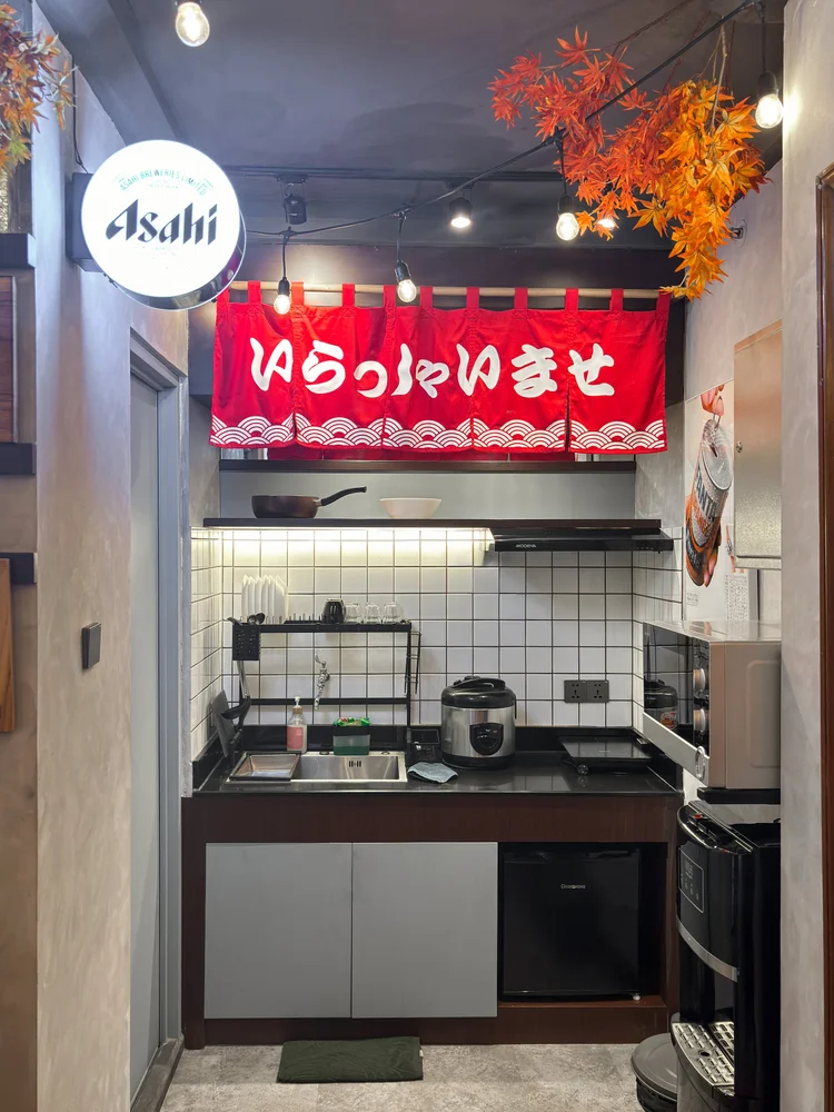 Shinjuku: Open kitchen with induction stove and rice cooker, under a Japanese shop-front sign.
