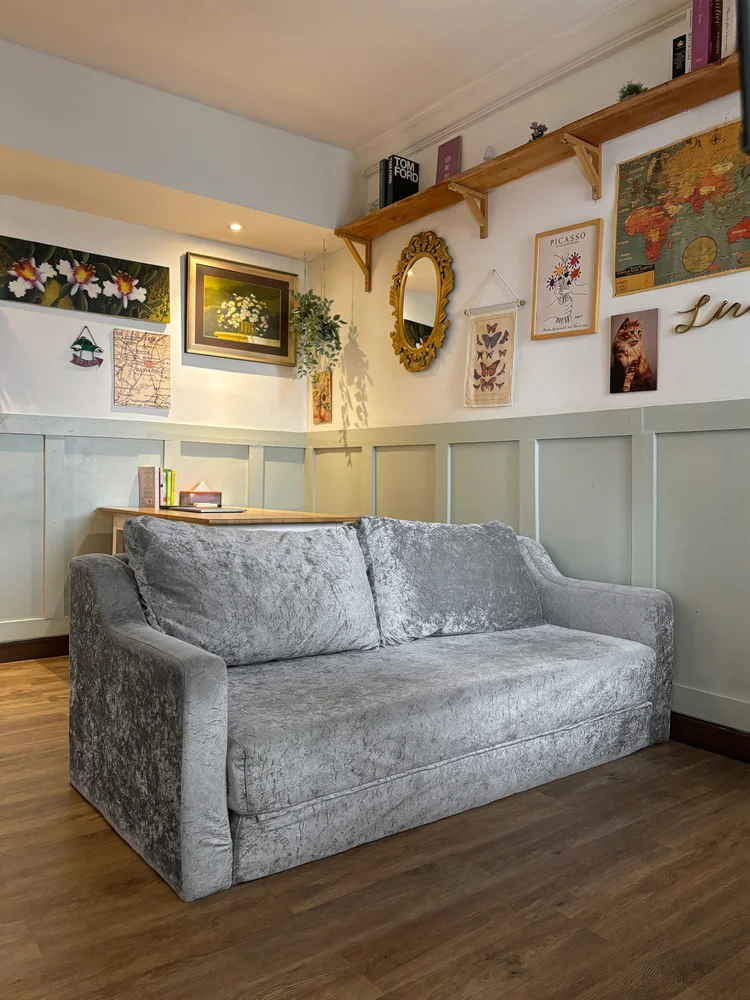 Florence: A soft sofa in the living room, facing the French-style wall decor.
