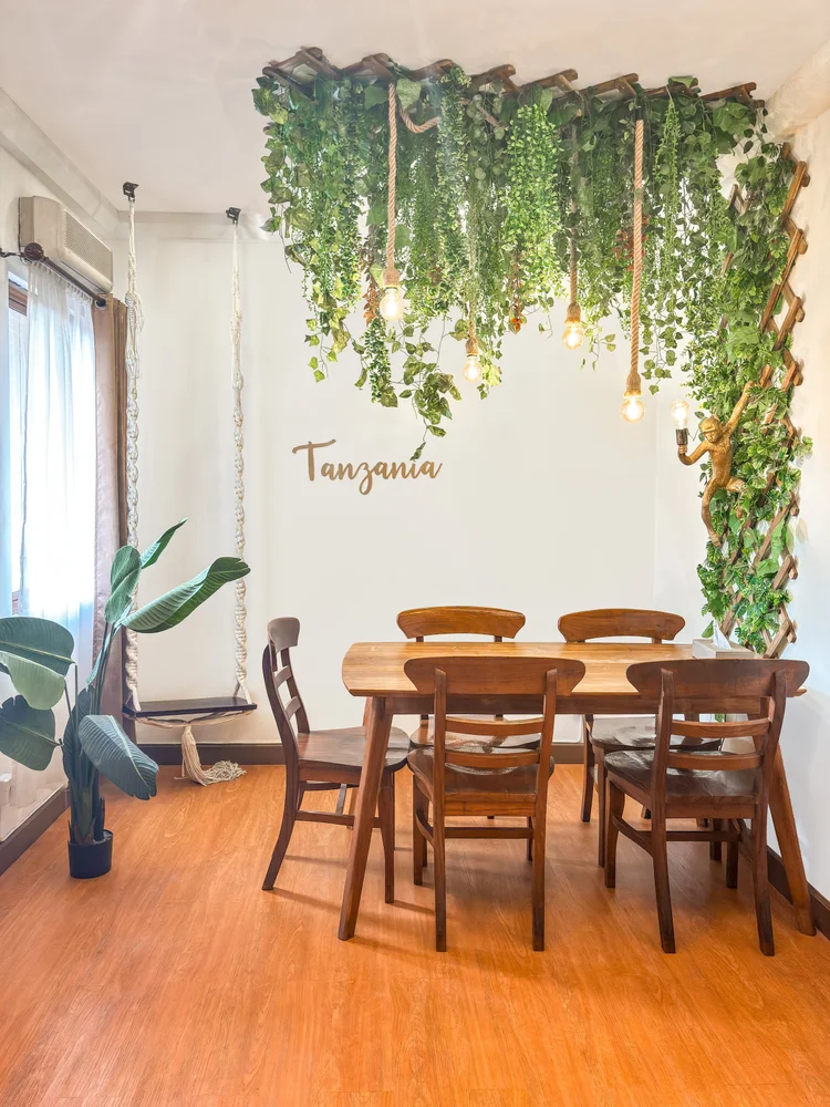 Tanzania: Dining table for five under the hanging plants, the open kitchen to the right.