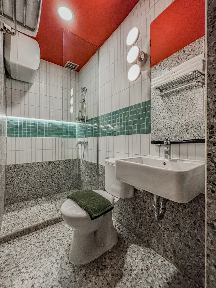 Hong Dae: A hot-water shower, terrazzo floor and green tiles.