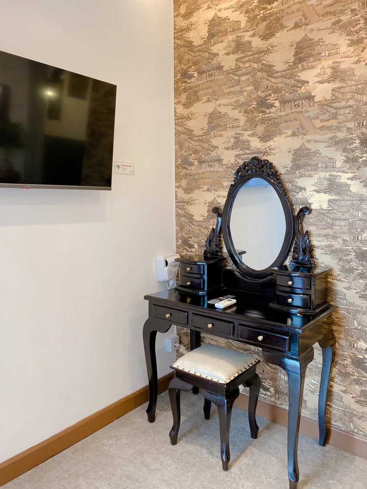 Saigon: Smart TV on the wall and a carved black dressing table with an oval mirror.