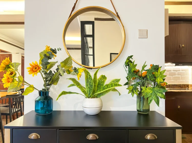 Norfolk: A black console with sunflowers and a round mirror near the kitchen.