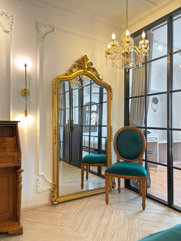 Paris: A gold mirror and classic chair beside the black glass partition to the bedroom.