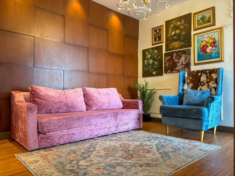 Marseille: Marseille's living room: a velvet sofa, a wing chair and paintings on the wood wall.