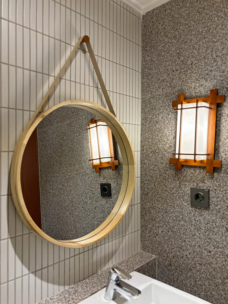 Nami: A round mirror and Korean-style wall lamps in the bathroom.