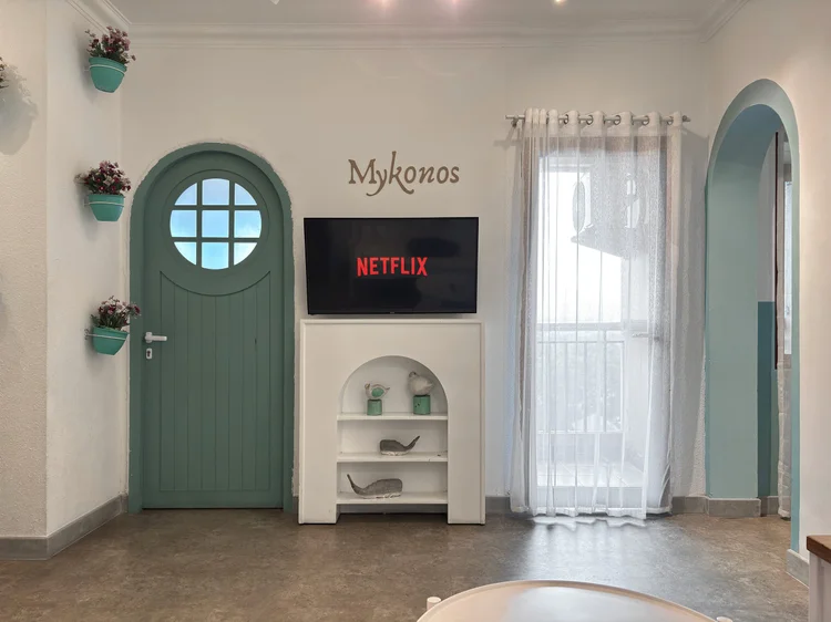 Mykonos: A blue porthole door and smart TV. Sleeps 8, up to 12 with extra beds.