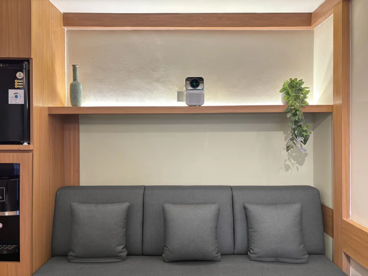 Kawaguchi: A three-seater sofa facing the screen, the smart projector on the shelf above.