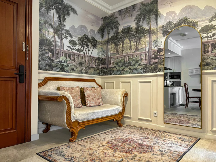 Batavia: Two-seater sofa under the tropical mural, with a full-length mirror beside it.