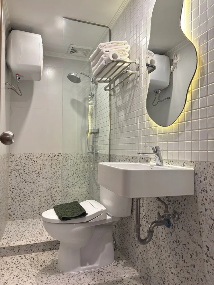 Seoul: Modern bathroom with terrazzo floor, basin and toilet; the same soap and shampoo in every unit.