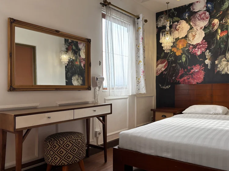 Marseille: Dressing table with a large mirror and stool, against the floral wall.