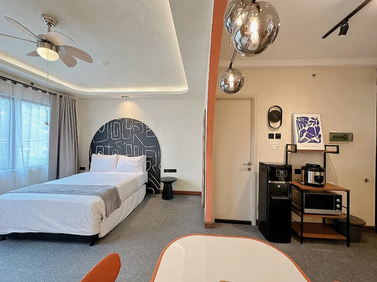 New York: The bed by the window, a ceiling fan above, the kitchen a few steps away.