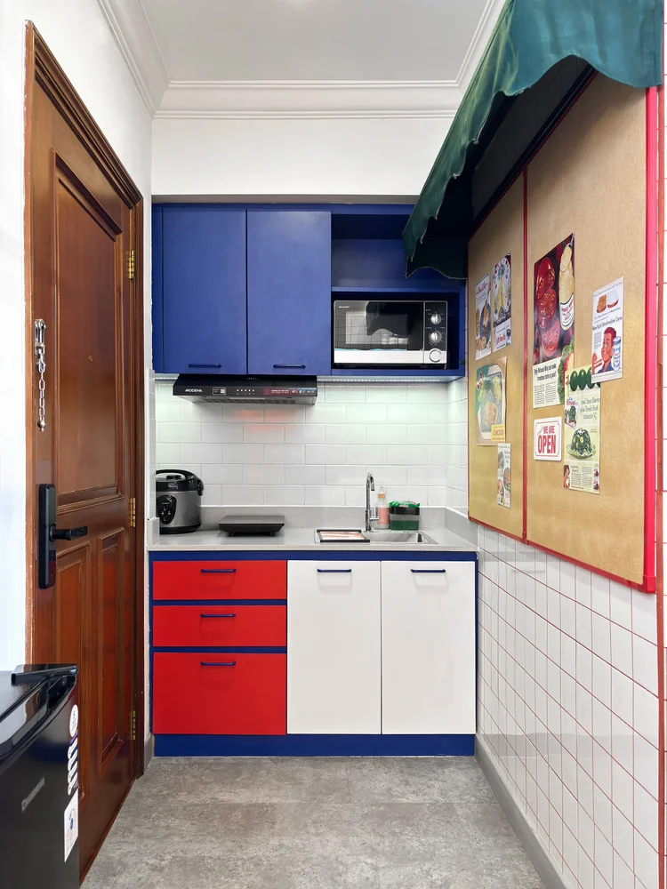 Miami: Open kitchen in blue and red cabinets, with microwave and induction hob.