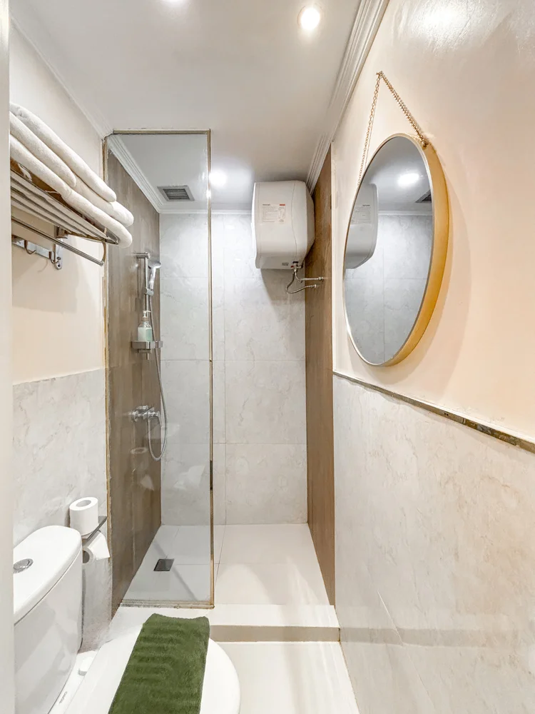 Provence: Bathroom with a hot-water shower and a round gold-framed mirror.