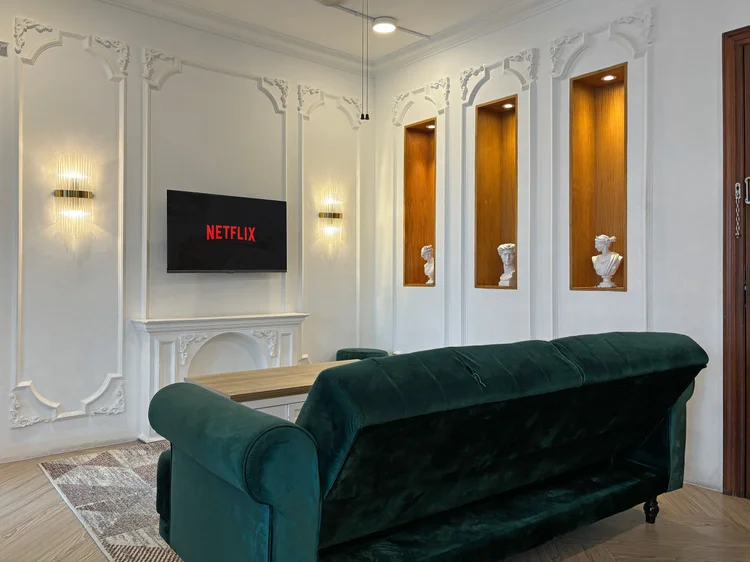 Paris: The living room: a green velvet sofa, smart TV with Netflix and niches with busts.