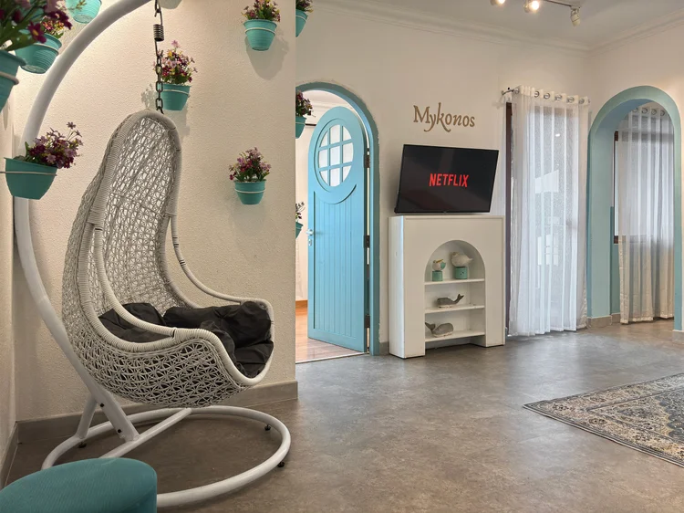 Mykonos: A white rattan hanging chair by the Mykonos-blue door.