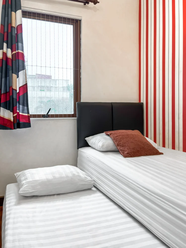 Amsterdam: A single bed by the window, with red and blue patterned curtains.