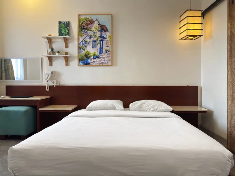 Santorini: A bedroom with a 160 cm queen bed, wall shelves and our standard white sheets.