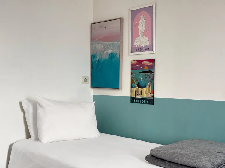 Santorini: A bedroom with a single bed, teal wainscot and Santorini prints.