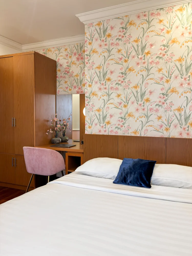 Salzburg: A bedroom with floral wallpaper, a wardrobe and the white sheets standard in all our units.