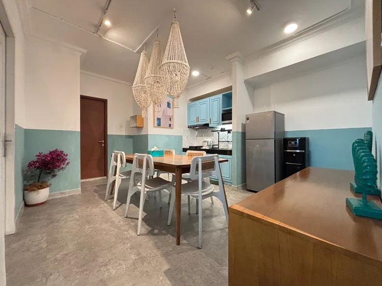 Mykonos: Dining table and open kitchen in one room, a fridge with freezer in the corner.