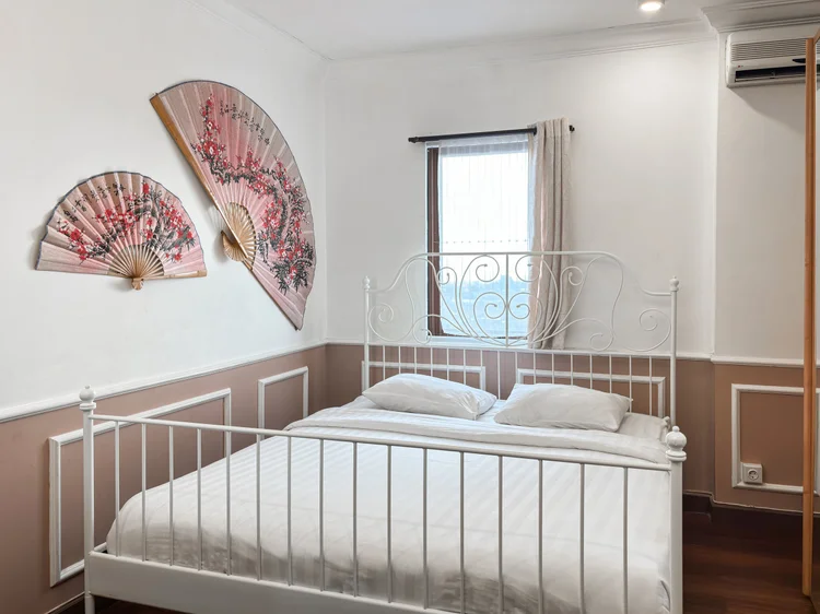 Salzburg: A bedroom with a white iron bed and fan ornaments on the wall, its own AC.
