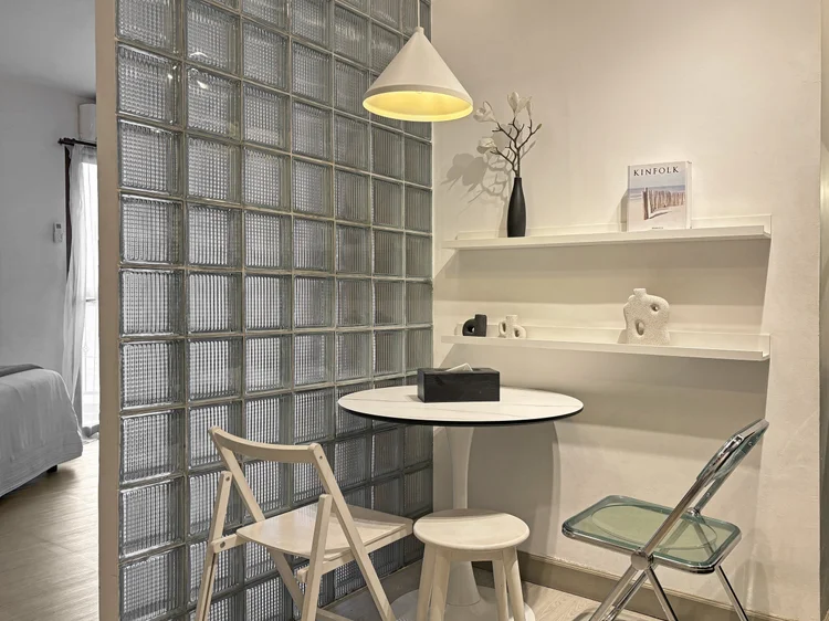 Sydney: A round dining table for three with folding chairs, under a pendant lamp.