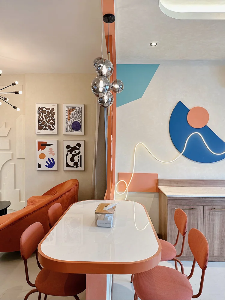 New York: An oval dining table with orange chairs, under the New York mural.