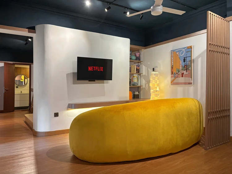 Kyoto: A curved yellow sofa faces the smart TV with Netflix, a cozy spot to unwind.