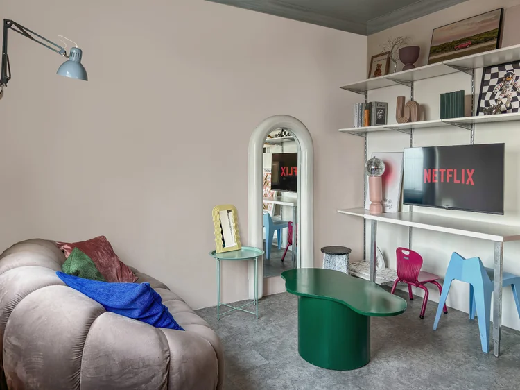 Vancouver: A spaceage living room: round grey sofa, green table, smart TV with Netflix.