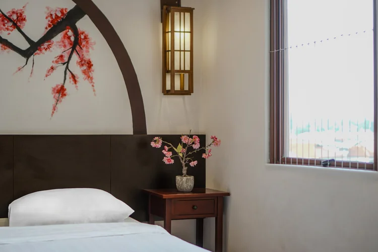 Yokohama: A bedroom with a single bed under the same cherry blossom mural, AC and a small nightstand.