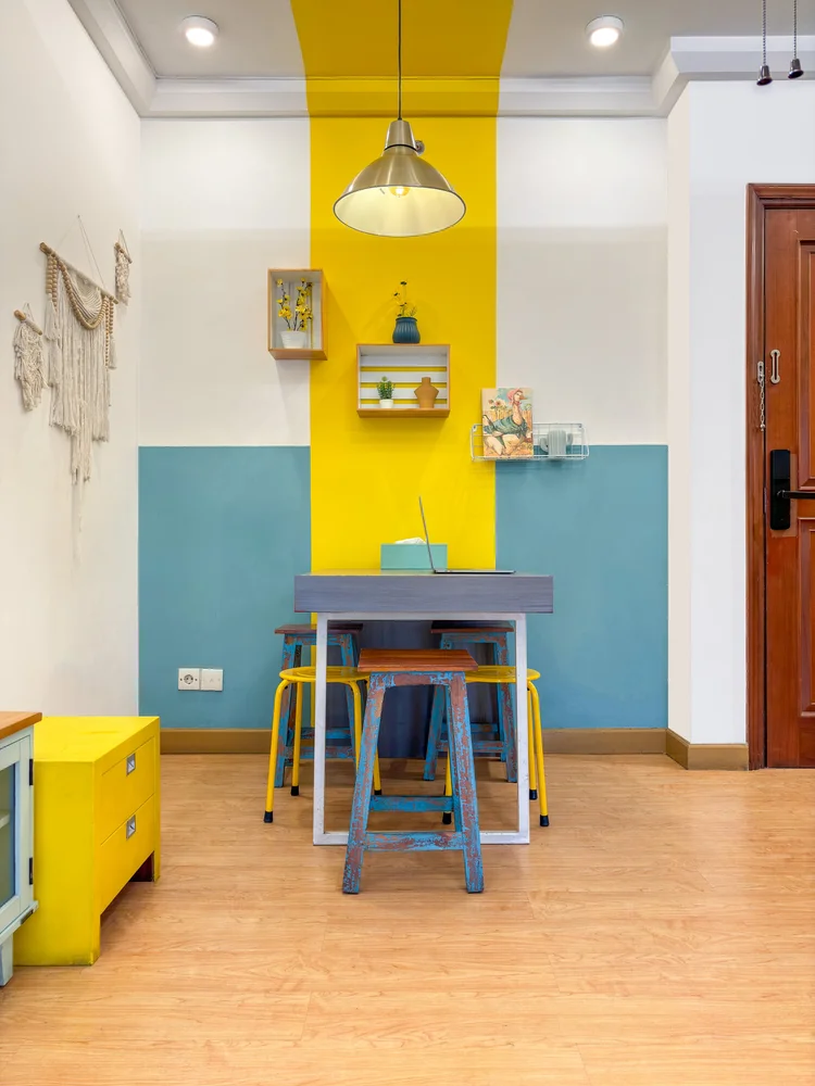 St. Tropez: Dining table for four with colourful stools, under a pendant lamp.