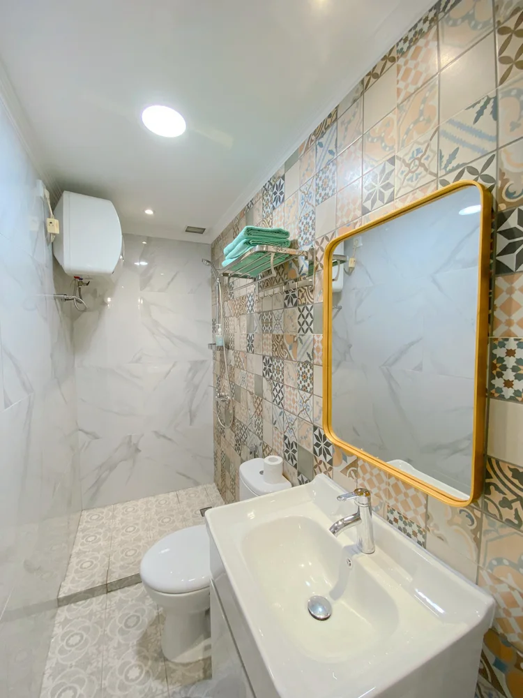 Cappadocia: Bathroom with patterned tiles and a gold mirror; soap and shampoo already stocked, the same in every unit.