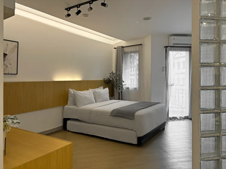 Sydney: Bed area with AC, a curtained window and a wood panel headboard.
